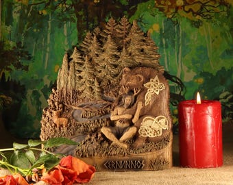 May include: A detailed wooden carving depicting a forest scene with a figure, deer, and bear. A red candle is lit beside the carving. The word "CERNUNNOS" is carved at the base. Red roses are in the foreground.