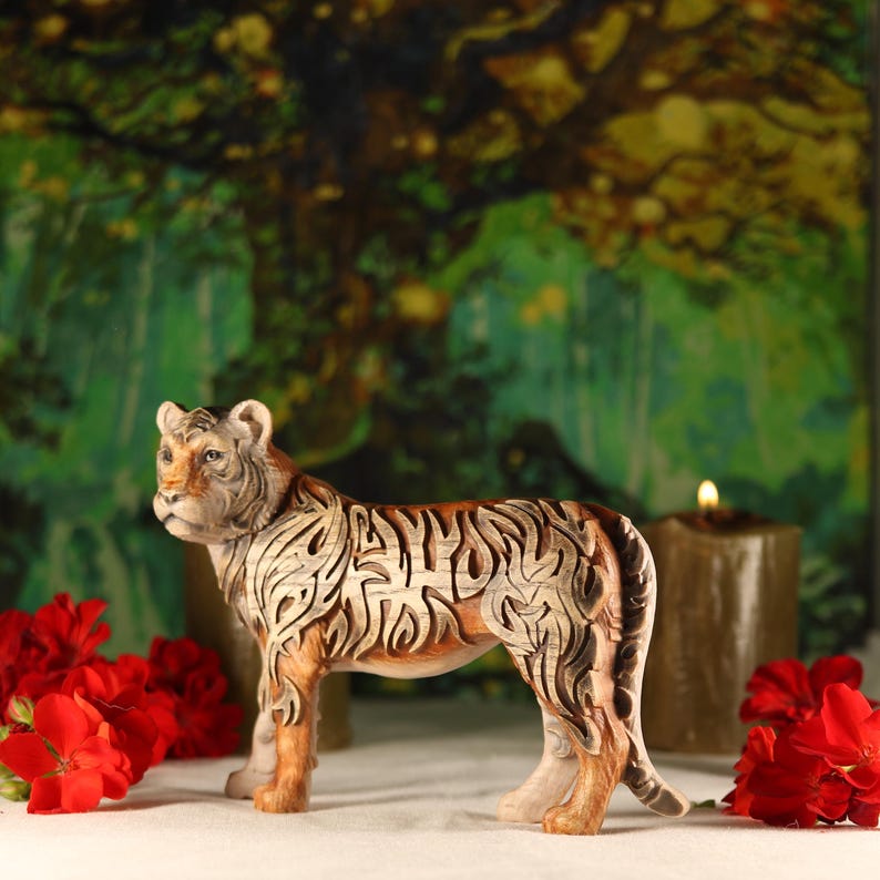 May include: A wooden tiger figurine with intricate carvings, standing on a white surface with red flowers in the background.