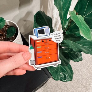 May include: A sticker of a red medical cart with a monitor, a tank of oxygen, and a speech bubble that says "It sure is quiet around here".