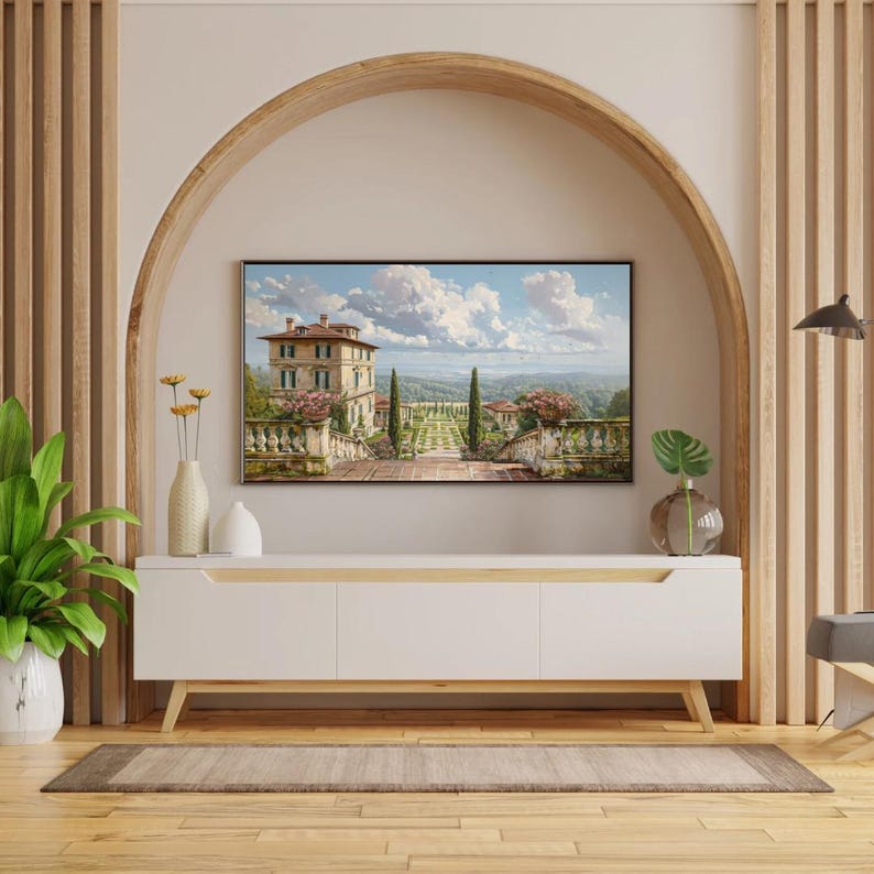 May include: A white modern TV stand with wooden legs and a light wood trim. A framed landscape painting hangs above the stand. Decorative vases and plants are on the stand. The room has wooden accents and flooring.