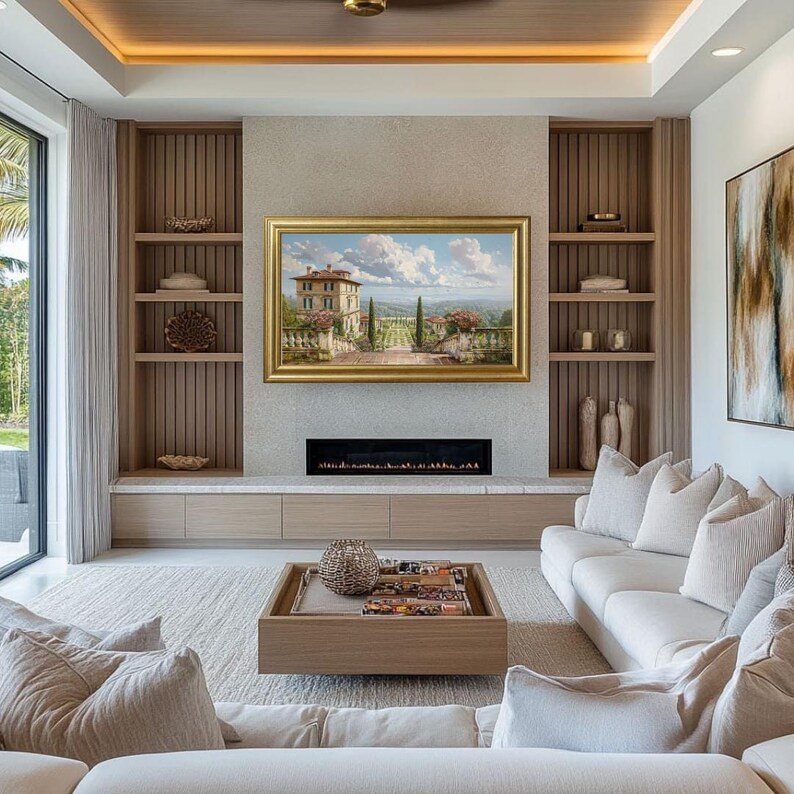 May include: A luxurious living room with a neutral color palette. A landscape painting in a gold frame hangs above a fireplace. Built-in shelves flank the fireplace. A wooden coffee table sits on a light-colored rug in front of a white sofa.