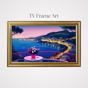 Puede incluir: Una impresión artística enmarcada titulada "TV Frame Art" representa una escena costera al anochecer. La obra presenta una barandilla rosa, una mesa con una maceta y una vista de una ciudad con luces a lo largo de la costa. El marco es dorado.