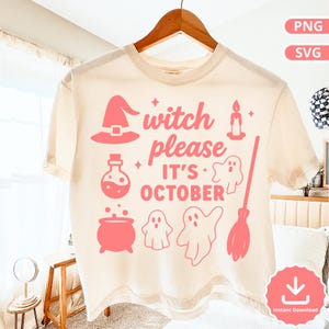 Può includere: T-shirt color crema con grafica rosa a tema Halloween. La grafica include un cappello da strega, una bottiglia di pozione, un calderone, fantasmi, una scopa e la scritta "witch please it's October". La maglietta è appesa a una gruccia di legno.