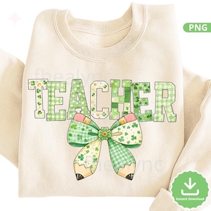 May include: Cream-coloured sweatshirt featuring the word "TEACHER" in green, clover-patterned letters. A bow-tie shaped pencil design with green and pink accents is centered below the word. The design is a PNG file.