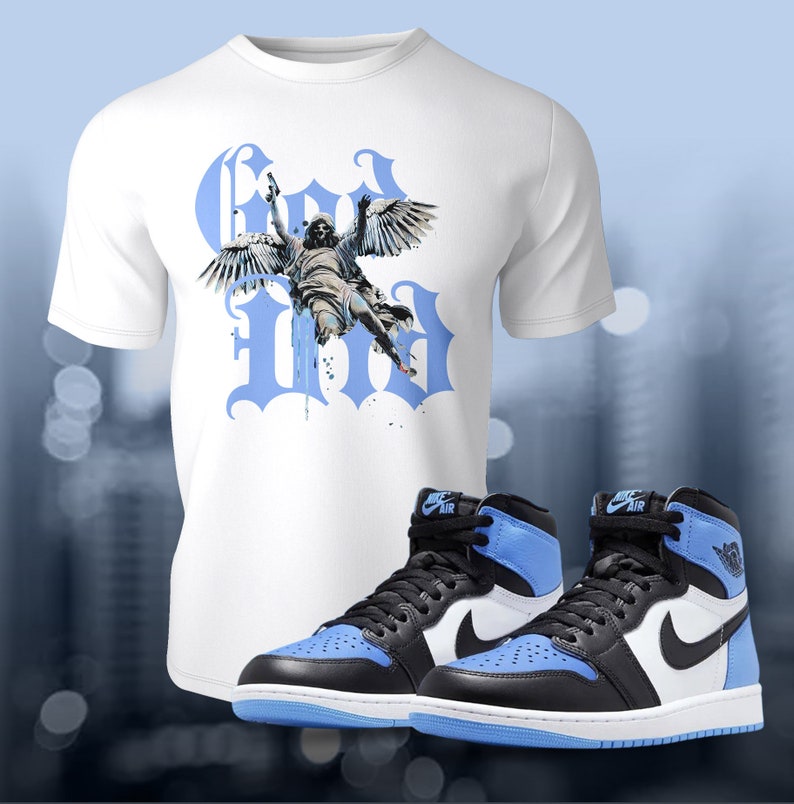 May include: White t-shirt featuring a blue graphic of an angel with wings and the word "God" in blue lettering. A pair of black and blue high-top trainers with a white swoosh logo.