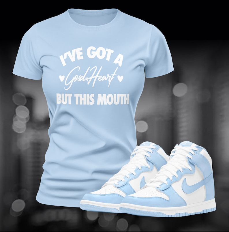 May include: A light blue t-shirt with the text "I've got a Good Heart but this mouth" in white. A pair of light blue and white high-top sneakers are below the shirt.
