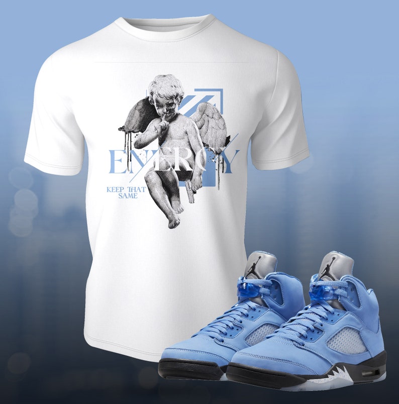 Pu&ograve; includere: Maglietta bianca con una grafica di un cherubino e il testo "ENERGY" e "KEEP THAT SAME". Un paio di scarpe da ginnastica blu chiaro con accenti neri e bianchi.