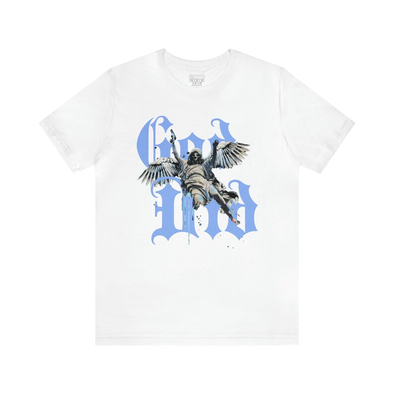 May include: White t-shirt featuring a blue graphic print of an angel with wings, flying through the air. The graphic is styled with the word "God" in large, gothic letters.