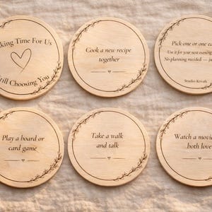 May include: Six circular wooden coasters with black text, such as "Making Time For Us" and "Take a walk and talk." Each coaster features a floral border and a small heart symbol. Ideal for a gift.