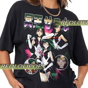 Könnte beinhalten: Schwarzes T-Shirt mit einer farbenfrohen Anime-Grafik, die mehrere Charaktere und japanischen Text enthält. Das Design zeigt Anime-Charaktere mit grünen Haaren, die schwarze und weiße Outfits tragen. Der Text "REDLOLIPOP" ist auf das T-Shirt gedruckt.