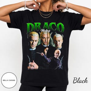 May include: A black t-shirt featuring a graphic print of Draco Malfoy in four different poses. The text "DRACO" appears in large green letters at the top, with "Malfoy" in white script below. The design includes lightning bolt accents.