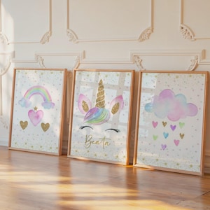 Peut inclure: Trois impressions d'art encadrées sur le thème fantaisiste. L'une présente un arc-en-ciel, des cœurs et des paillettes dorées. Une autre présente une licorne avec une corne dorée et le nom "Beata". La troisième affiche un nuage avec des cœurs.