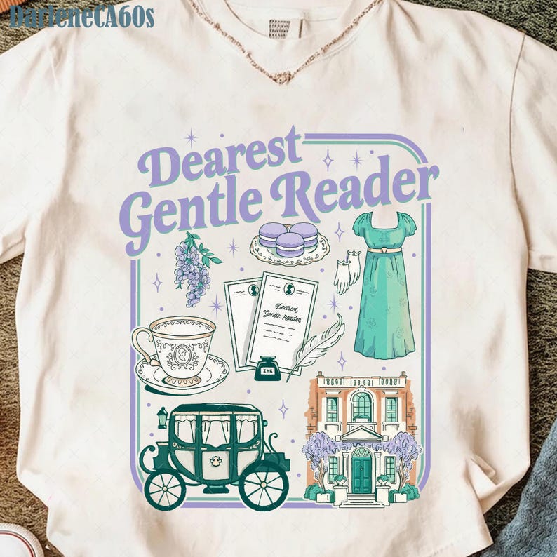 May include: Cream t-shirt with a graphic design that reads "Dearest Gentle Reader." The design features illustrations of a dress, carriage, teacup, and other elements in shades of purple, green, and white.