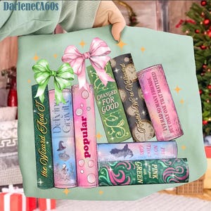 Puede incluir: Un bolso tote verde claro con un diseño de libros apilados, incluyendo títulos como "The Wizard And I" y "Popular". Los libros están adornados con lazos y motivos de estrellas. El texto "DarleneCA60s" es visible en la esquina superior izquierda.