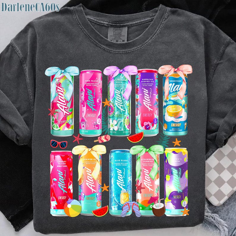 May include: Dark gray sweatshirt featuring colorful Alani Nu energy drink cans with various flavors. Each can is adorned with a decorative bow and tropical-themed graphics, including fruit slices and beach accessories.