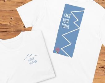 May include: Two white t-shirts with different designs. The front shirt has a blue mountain range with the text "Skin Up Ski Down". The back shirt has a blue rectangle with a white zig-zag line and the text "Earn Your Turns".