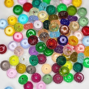 May include: A large assortment of colorful, sparkly, round beads with a hole in the center. The beads are made of glass and have a textured surface.