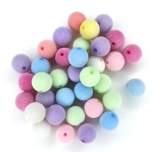 May include: A collection of pastel-colored foam beads. The beads are round and have a slightly textured surface. The colors include light blue, light green, light pink, light purple, and white.
