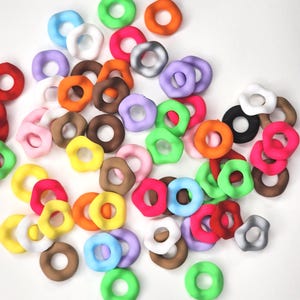 May include: A collection of colorful, plastic, donut-shaped rings. The rings are in various colors, including red, orange, yellow, green, blue, purple, pink, brown, black, and white.