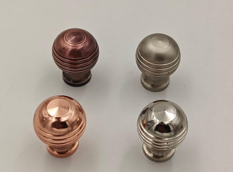 Puede incluir: Cuatro pomos de armario con un dise&ntilde;o redondo y estriado. Dos son de cobre, uno es de n&iacute;quel cepillado y uno es de n&iacute;quel pulido.