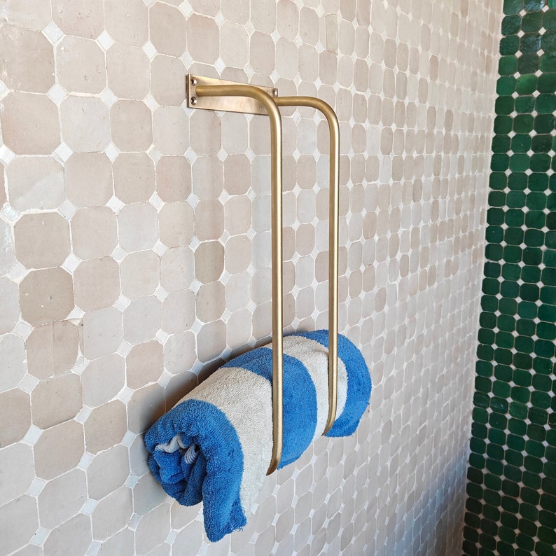 Lifestyle image: bathroom scene with matching unlacquered brass fixtures—towel rack, faucet, and shower hardware; cohesive antique brass bathroom décor that elevates farmhouse, cottage, or modern minimalist interiors; easy wall-mount towel storage solution.