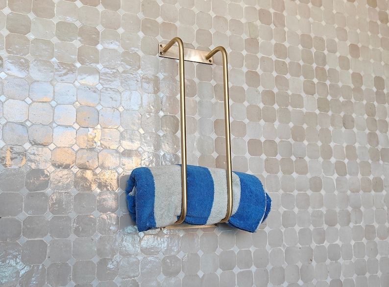Close-up of antique brass towel bar showing unlacquered solid brass finish and sturdy mounting brackets; perfect for hanging hand towels, bath towels, or washcloths; sleek minimalist design blends farmhouse, industrial, and French-country styles.