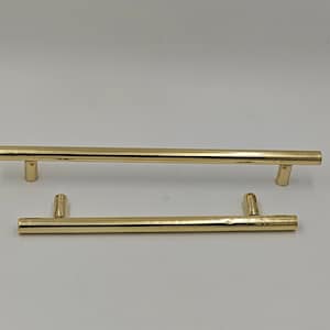 May include: Two gold-toned metal cabinet door pulls. The top pull is longer than the bottom pull.
