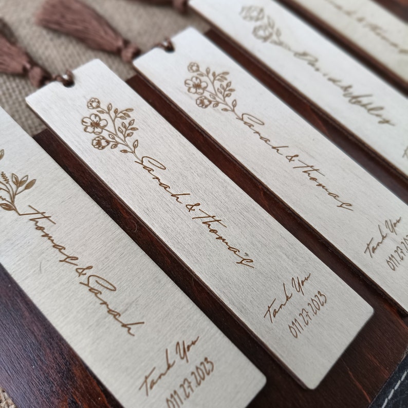 Pode incluir: Marcadores de madeira com um design floral e o texto "Sarah & Thomas" e "Obrigado 011.27.2023".