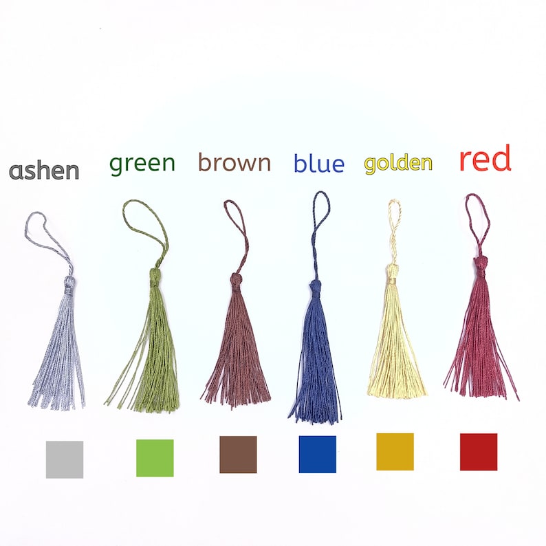 Pode incluir: Seis borlas de diferentes cores: cinza, verde, castanho, azul, dourado e vermelho. Cada borla &eacute; feita de um &uacute;nico fio de cor e tem um la&ccedil;o na parte superior.