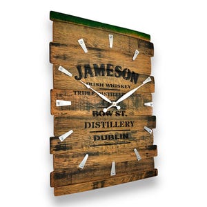 May include: A rectangular wall clock made from reclaimed wood, featuring the Jameson Irish Whiskey logo and text. The clock has silver-colored hands and markers, and measures approximately 12 inches wide and 18 inches tall.