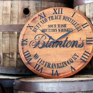 May include: A wooden clock face with Roman numerals and the text "Buffalo Trace Distillery, Sour Mash Bourbon Whiskey, Blanton's, No. 113 Franklin County" printed on it. The clock is made from a repurposed whiskey barrel.