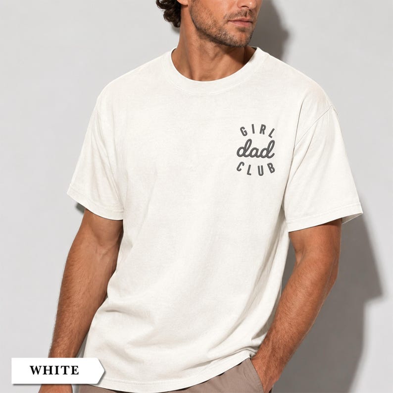 Puede incluir: Camiseta blanca de manga corta con el texto "GIRL dad CLUB" impreso en negro en la parte superior izquierda del pecho. La camiseta es de color blanco liso y tiene cuello redondo.