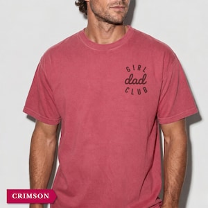 Puede incluir: Camiseta de manga corta color carmes&iacute; con la inscripci&oacute;n "GIRL dad CLUB" estampada en el pecho. La camiseta tiene cuello redondo y un aspecto ligeramente descolorido. La camiseta es de material suave.