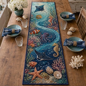Puede incluir: Un camino de mesa acolchado rectangular que presenta una vibrante escena submarina con una raya, caballitos de mar, un pulpo, una estrella de mar, peces payaso y arrecifes de coral en tonos azules, naranjas y rosas, con borde azul.