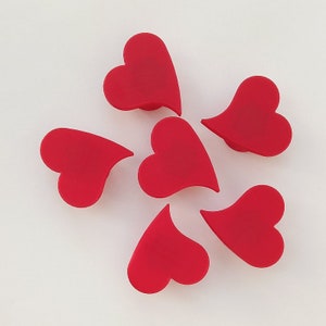 Könnte beinhalten: Sechs rote herzförmige Objekte aus glattem, festem Material. Die Herzen sind in einem Kreis auf weißem Hintergrund angeordnet.