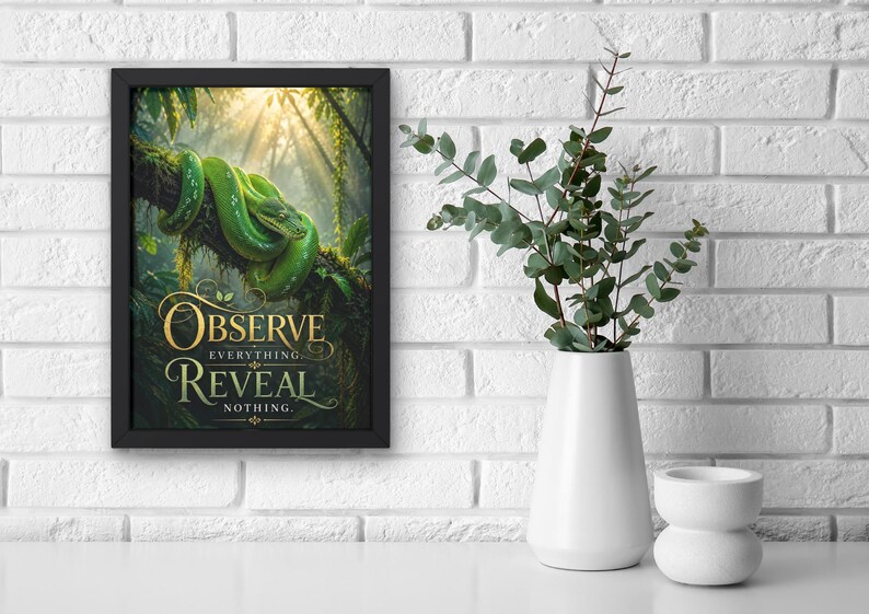 May include: A framed wall art print featuring a vibrant green snake coiled on a tree branch in a sunlit jungle setting. The text "OBSERVE EVERYTHING REVEAL NOTHING" is printed in elegant gold lettering at the bottom of the rectangular artwork.