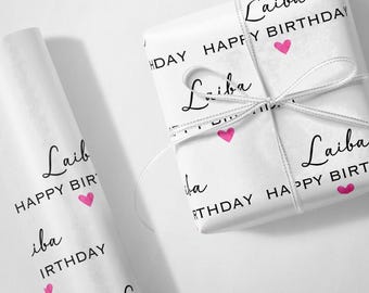 May include: White wrapping paper with a repeating pattern of the name "Laiba" and the phrase "Happy Birthday" in black text with pink hearts.