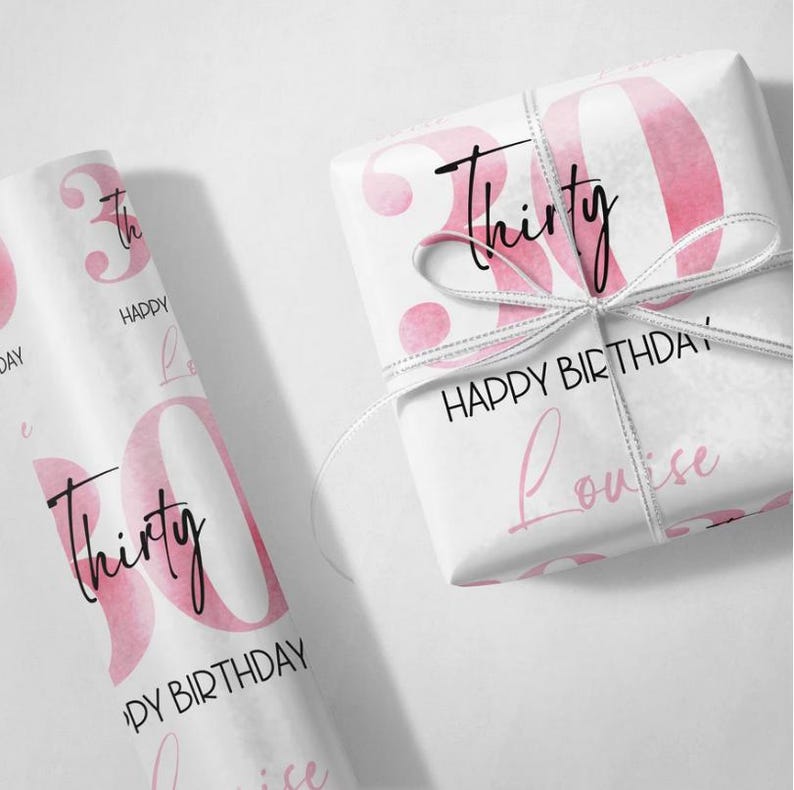 以下が含まれることがあります： ピンクと白の包装紙に、数字の30と「Thirty」と「Happy Birthday」の文字が印刷されています。また、「Louise」という名前も印刷されています。
