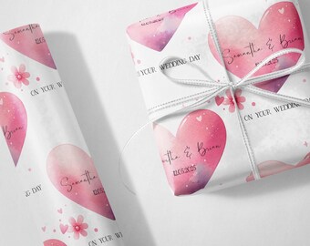 May include: White wrapping paper with a watercolor heart design in shades of pink and purple. The paper is decorated with small hearts and flowers, and the text "Samantha & Brian 12.05.2025" is printed on the paper. A roll of matching paper is also visible.