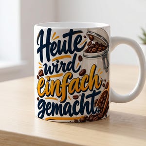Può includere: Una tazza in ceramica bianca con il testo in tedesco "Heute wird einfach gemacht" in corsivo blu scuro e giallo. Il design include l'illustrazione di un barattolo di vetro pieno di chicchi di caffè marroni e un cucchiaio di legno.