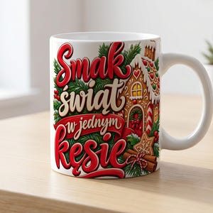 Può includere: Una tazza in ceramica bianca con una grafica colorata di una casa di pan di zenzero, rami di pino e bastoncini di cannella. Il testo "Smak świat w jednym kęsie" è stampato in grandi lettere stilizzate rosse e crema sul davanti.