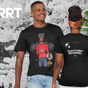 Può includere: Maglietta nera con una grafica bianca di un uomo con una camicia rossa e il testo "GIGGS" con una bandiera dell'Unione Jack sopra il testo. La parte posteriore della maglietta ha un testo bianco che dice "If you're talkin' the hardest..."
