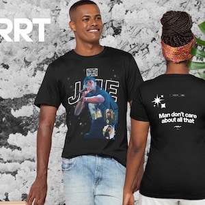 Può includere: T-shirt nera con una grafica di un rapper sul davanti e il testo "J. Cole" sul davanti. La parte posteriore della maglietta ha il testo "Man don't care about all that" e una grafica a stella.