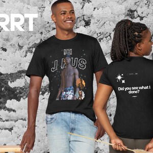 Può includere: Due magliette nere con design diversi. La parte anteriore di una maglietta presenta un'immagine in bianco e nero di un uomo con il testo "J HUS" sopra di lui. La parte posteriore dell'altra maglietta presenta un design a stella bianca e il testo "Did you see what I done?"