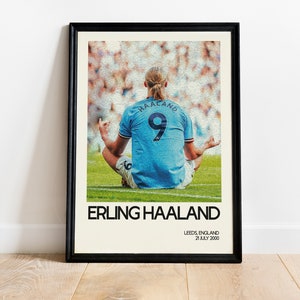 May include: A poster featuring a photo of Erling Haaland, a soccer player, sitting in a meditative pose on a green field. The poster has a white background with black text that reads "Erling Haaland", "Leeds, England", and "21 July 2000".