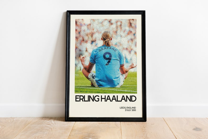 May include: A poster featuring a photo of Erling Haaland, a soccer player, sitting in a meditative pose on a green field. The poster has a white background with black text that reads "Erling Haaland", "Leeds, England", and "21 July 2000".