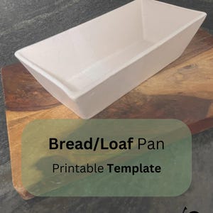 Puede incluir: Una bandeja rectangular para pan de color blanco roto, colocada sobre una tabla de cortar de madera. El texto "Bread/Loaf Pan Printable Template" es visible en la imagen. El logotipo de Cufe Ceramics está en la esquina inferior derecha.