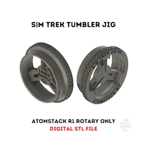 Puede incluir: Un jig impreso en 3D para un grabador láser rotatorio, diseñado para su uso con un Atomstack R1. El jig está etiquetado como "Sim Trek Jig V4" y "Atomstack R1".