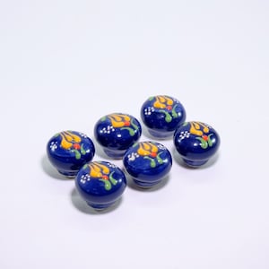 Pode incluir: Seis botões de armário de cerâmica azul com desenhos florais amarelos, verdes e vermelhos.
