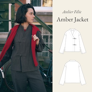 May include: A dark gray Amber Jacket with a mandarin collar and two toggle closures. The jacket is paired with matching pants. A red scarf is draped over the shoulders. The image also includes a line drawing of the jacket.